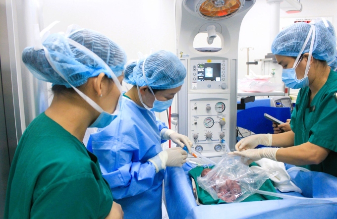 Bé chào đời được giữ ấm thân nhiệt, bác sĩ Dung (giữa) hồi sức sơ sinh ngay tại giường sinh, ảnh: Tuệ Diễm