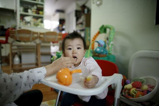 Một người phụ nữ đang cho con ăn tại nhà riêng ở Seoul, Hàn Quốc, tháng 7/2016. Ảnh: Reuters