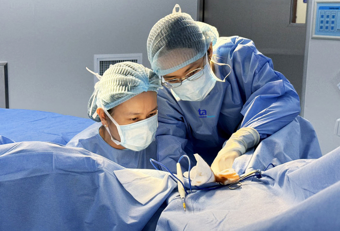 Bác sĩ Phương An (trái) phẫu thuật sửa dị tật vùng sinh dục cho bà Thoa. Ảnh: Tuệ Diễm