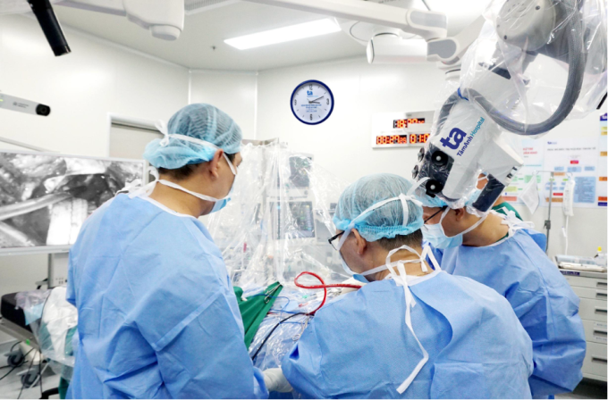 Bác sĩ Tấn Sĩ và cộng sự mổ cấp cứu đột quỵ xuất huyết não bằng phương pháp ENRICH với hỗ trợ của robot. Ảnh: Bệnh viện cung cấp