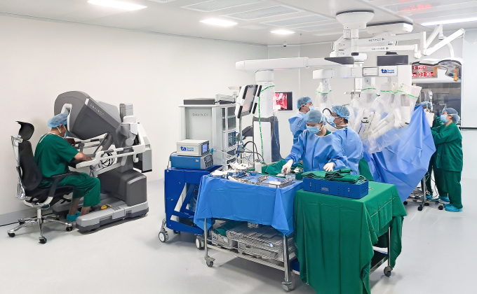 Phó giáo sư Chuyên (trái) ngồi ở buồng điều khiển robot Da Vinci Xi để phẫu thuật cho người bệnh. Ảnh: Bệnh viện Đa khoa Tâm Anh